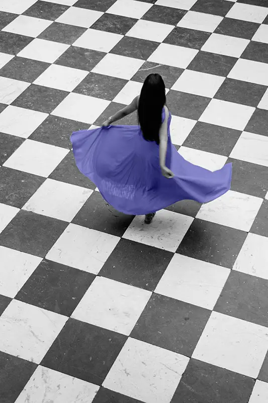 woman swirling her purple dress in a dance move on a checkered floor