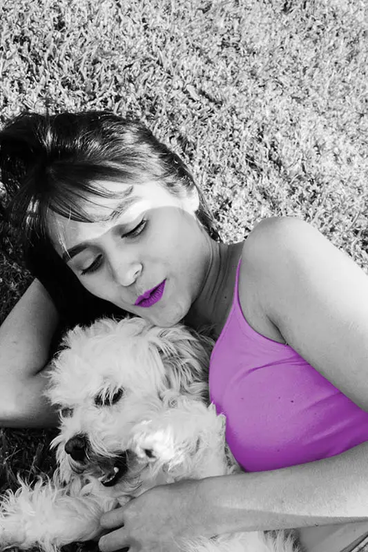 Woman in pink top cuddling a white dog, lying on the grass, abundance is also enjoying the little things 