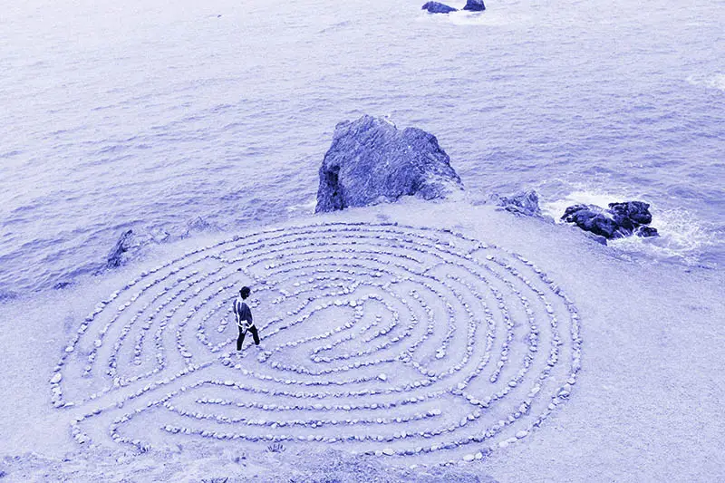 Person walkin in a labyrint on the beach made of stones as a metaphor for gaining a deeper understanding through spiritual practice