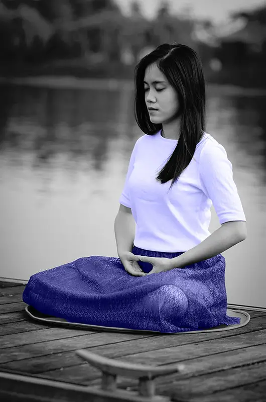 Woman meditating in nature by a lake