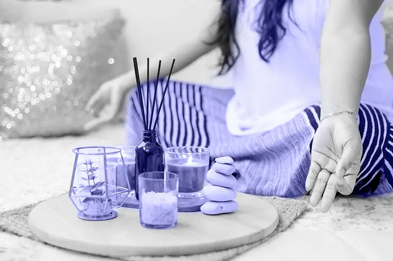 Meditating woman with incense sticks in front of her. By meditating regularly your raise your vibration