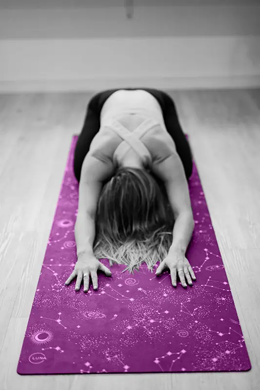 Woman in a yoga position on a pink yoga mat. Practicing yoga can raise your vibration